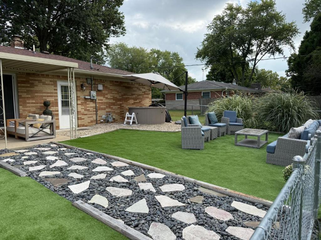 a backyard with a patio with chairs and grass at Delightful 3 Bd Home with King size bed, hot tub, playground! in Indianapolis