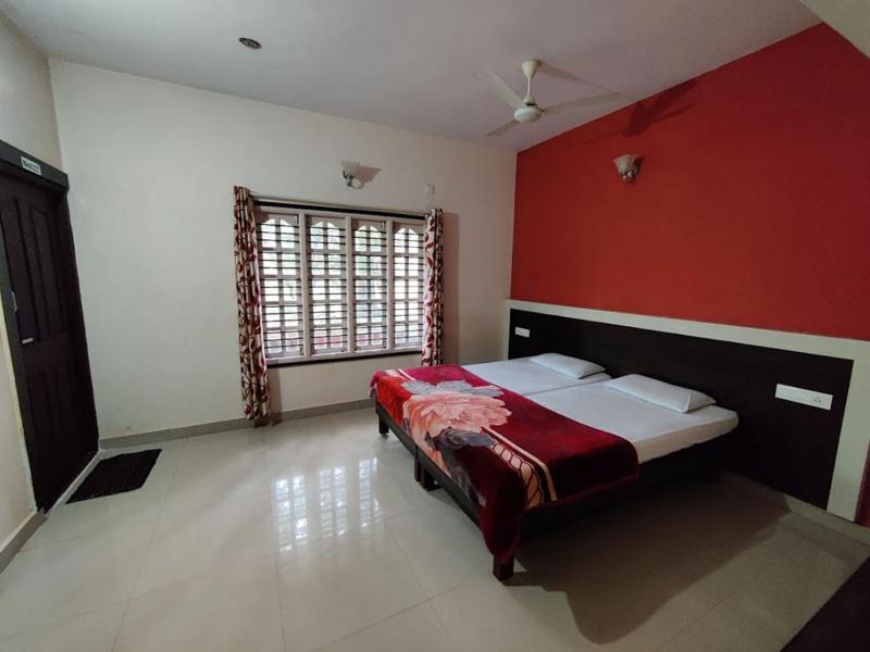 a bedroom with a bed with a red wall at Green Leaf Nature HomeStay in Santaveri