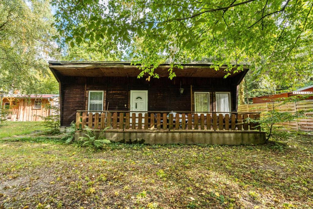 una pequeña casa con una valla de madera delante de ella en Bugalow 16 - Finnhütte, en Quitzdorf