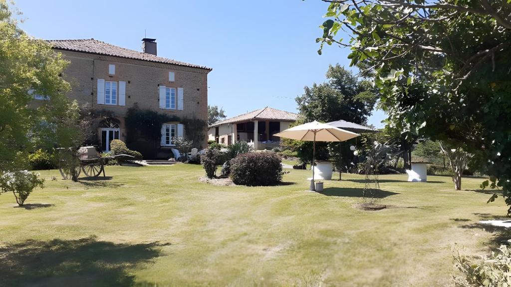 an umbrella in the yard of a house at Gite Le Marquès in Coueilles