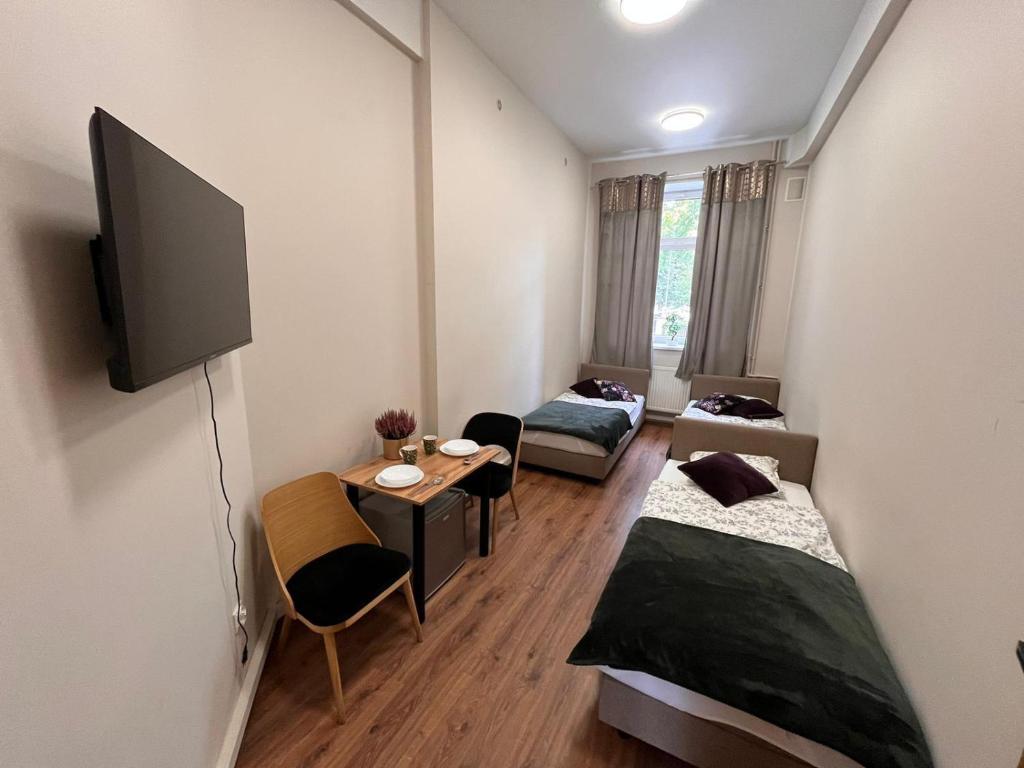 a room with two beds and a tv and a table at Hostel KASZUBSKA in Wrocław