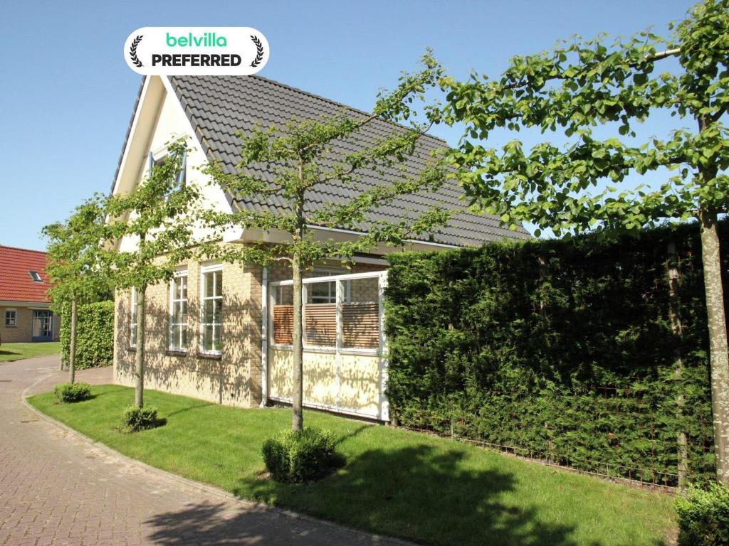 a small white house with a green hedge at Holiday Home in Schoorl near Sandy Beaches in Schoorl