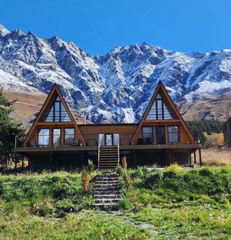 a log home with mountains in the background at Kazbegi Milla Cottages&Spa in Kazbegi