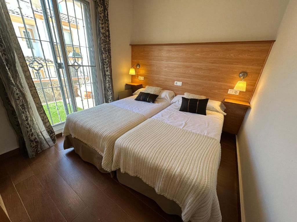 een slaapkamer met twee bedden en een groot raam bij Nevada Suites Guejar in Güéjar-Sierra