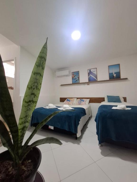 a room with two beds and a potted plant at POUSADA PARAISO da BARRA DA TIJUCA in Rio de Janeiro