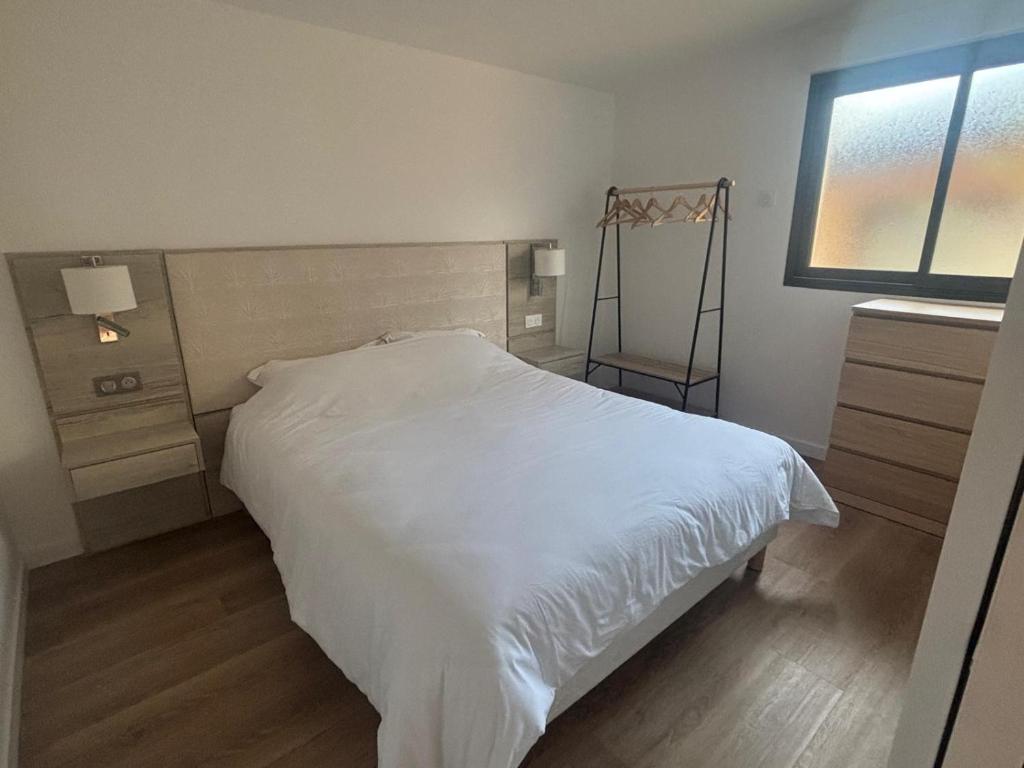 Un dormitorio con una cama blanca y una ventana. en DACSE-VILLAGE - Gite 01, en Dax