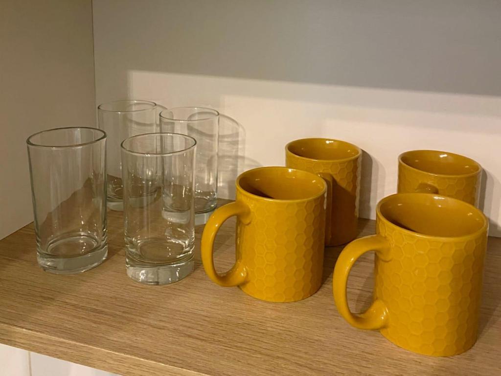 a row of yellow cups and glasses on a shelf at Lince Apartments in Lima