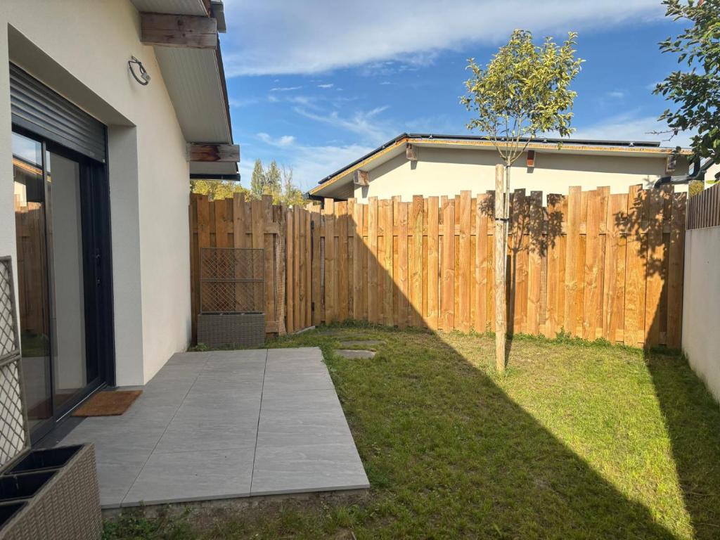 a backyard with a wooden fence and a sidewalk at DACSE-VILLAGE - Gite 03 in Dax