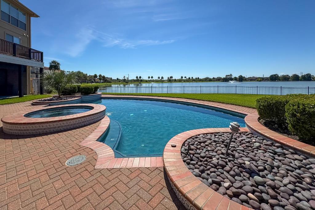 Una piscina con rocas alrededor junto a un lago. en Lakefront Houston House - 1 Mi to Space Center!, en Houston