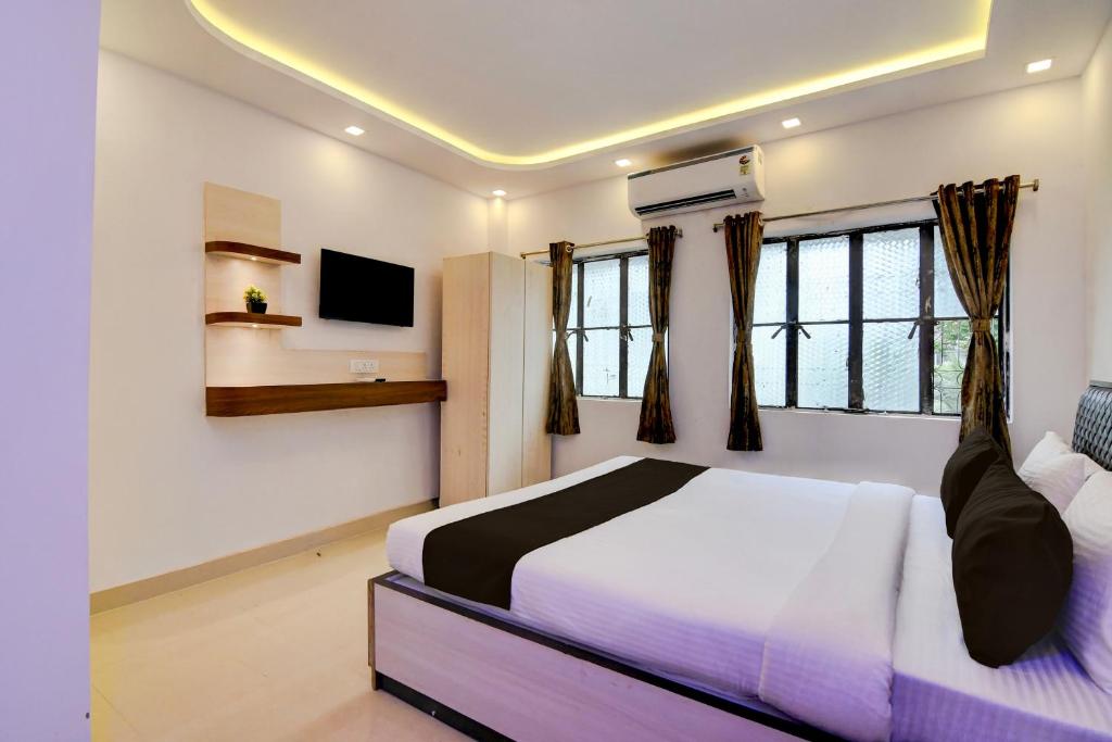 a bedroom with a bed and a tv and windows at Hotel O Acroview in Ballygunge