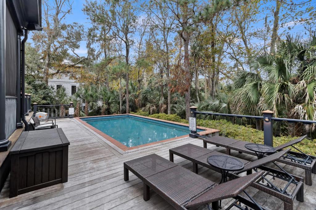 una terrazza con piscina, sedie e tavolo di SS162: 162 Surfsong Road a Kiawah Island