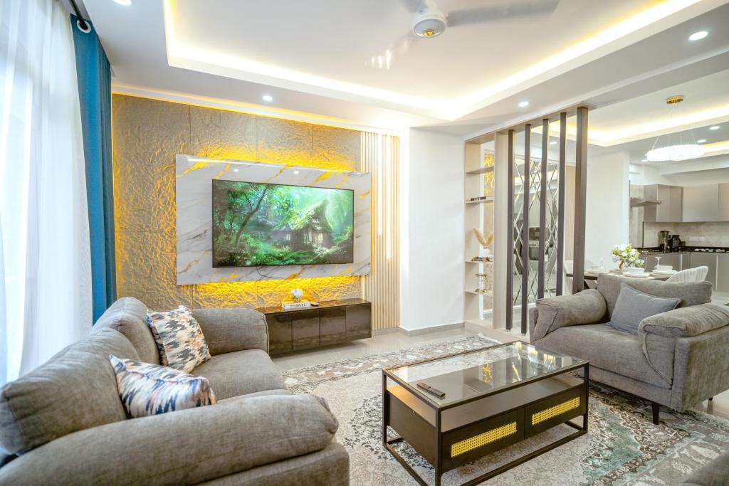 a living room with two couches and a tv on a wall at Bubbles Cozy Homes Two bedroom apartment in Mombasa