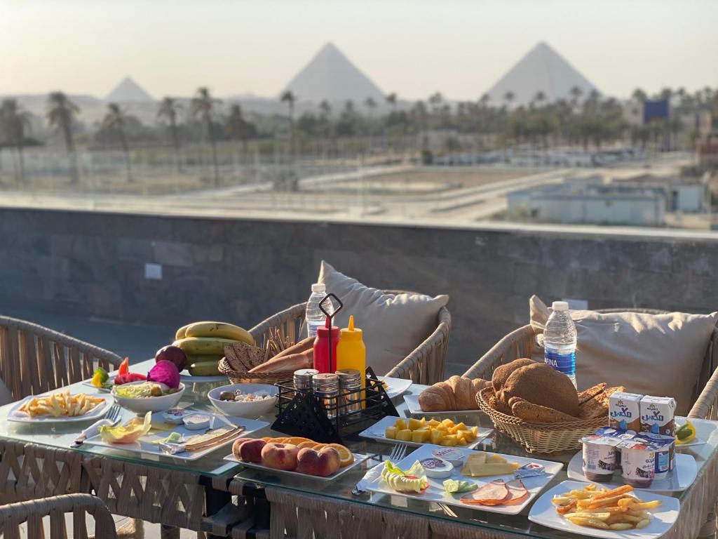 una mesa con comida en ella con pirámides en el fondo en New Galleria Pyramids Hotel, en El Cairo