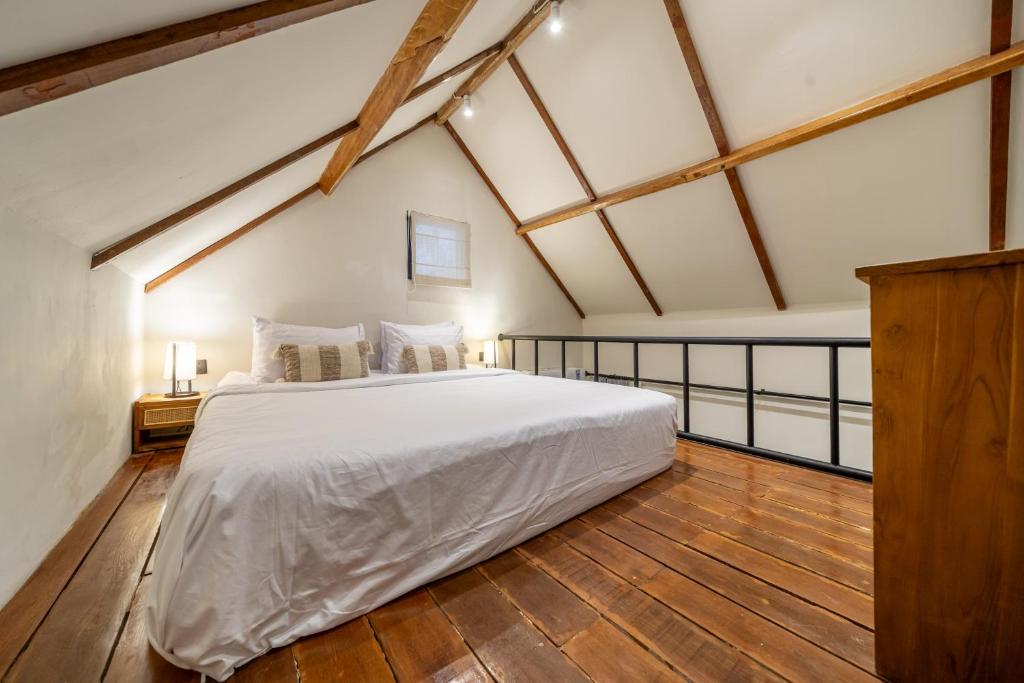 a bedroom with a large white bed and wooden floors at Balance, Beauty and WiFi - Find It All at Sarang Apartments 2 in Ubud