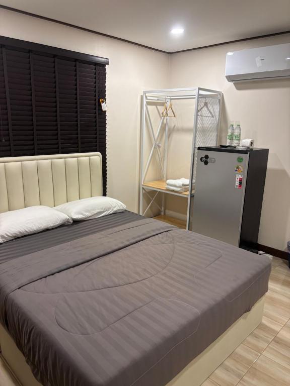 a bedroom with a large bed and a refrigerator at TheBloomMahasarakham in Maha Sarakham
