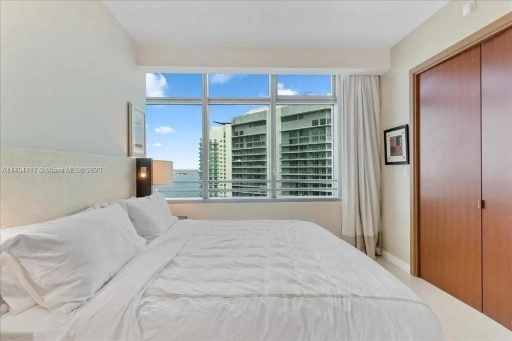 sypialnia z dużym łóżkiem i dużym oknem w obiekcie Lux Aka Brickell Condo w Miami