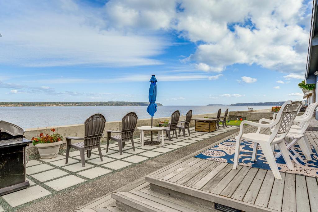 a deck with chairs and a table and an umbrella at Beachfront Whidbey Island Home and Apartment! in Langley