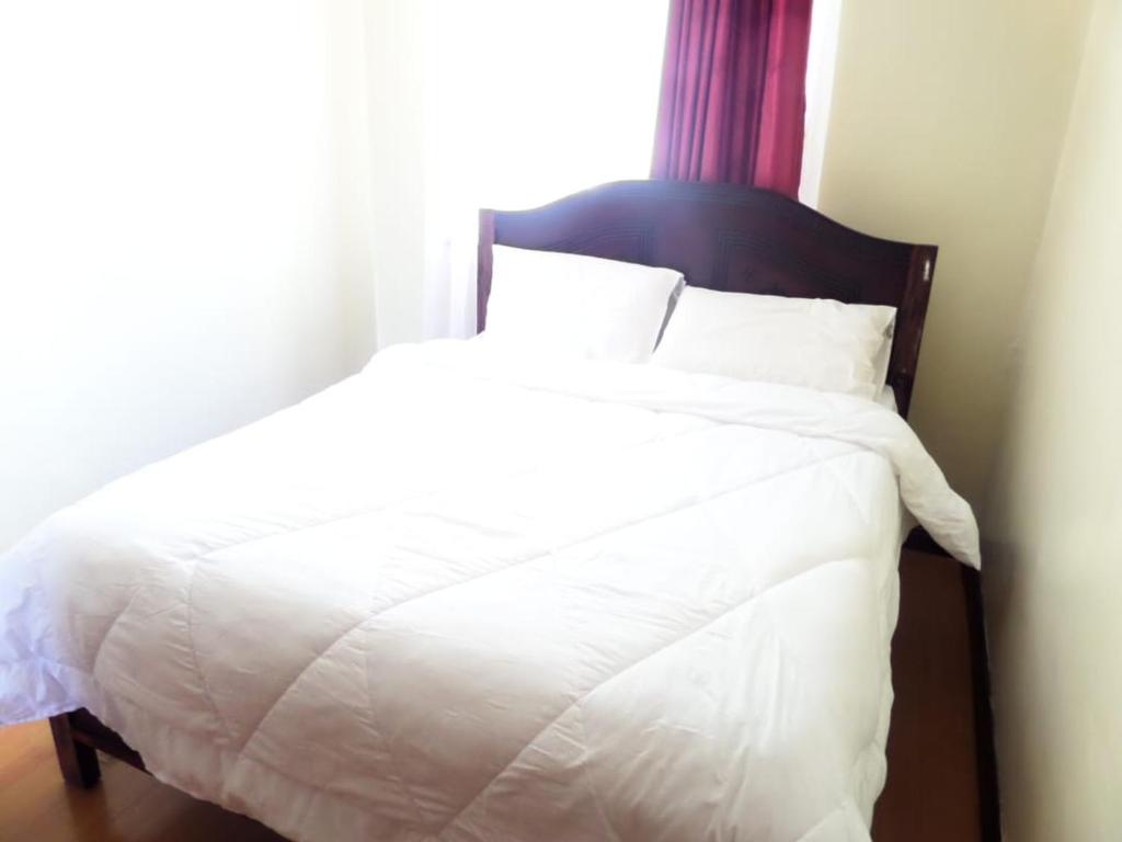 a bedroom with a white bed with a window at Sunshine in Nairobi