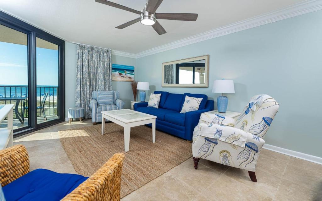 a living room with a blue couch and a table at Phoenix East 203 condo in Orange Beach