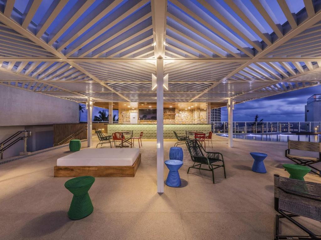 a pavilion with a bed and chairs on a roof at Novotel Salvador Rio Vermelho in Salvador