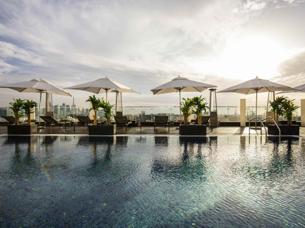 a swimming pool with umbrellas and tables and chairs at The Canvas Dubai - MGallery Hotel Collection in Dubai