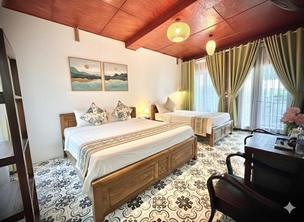 una camera d'albergo con due letti e una scrivania di Tam Coc Camellia Garden Homestays a Ninh Binh