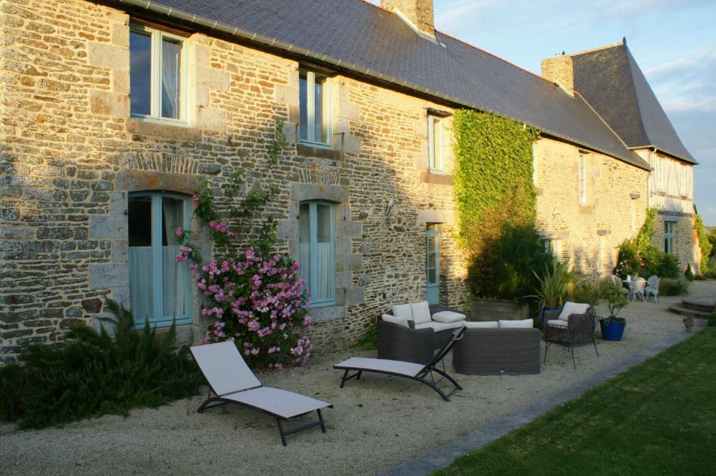 a brick building with chairs and tables in front of it at Le Clos Saint-Gilles in Ardevon