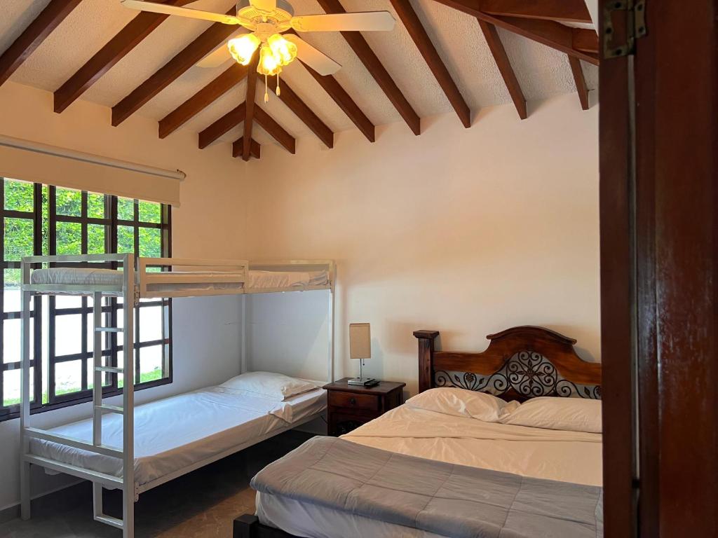 een slaapkamer met twee bedden en een plafondventilator bij Finca Hotel Gudys in Estación Belmonte