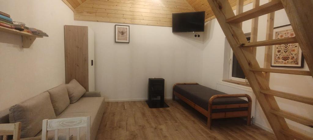 Una pequeña sala de estar con un sofá y un televisor. en Domek Czarnucha, en Augustów