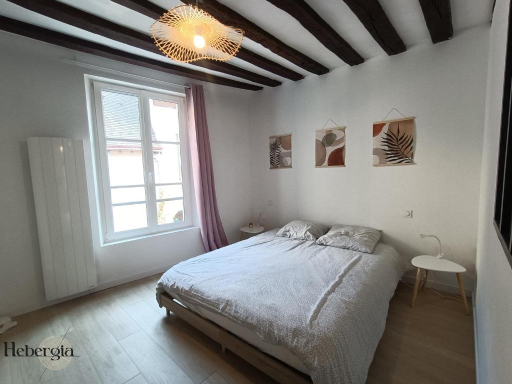 ein Schlafzimmer mit einem Bett und einem großen Fenster in der Unterkunft Maison basse-ville - centre historique in Chartres