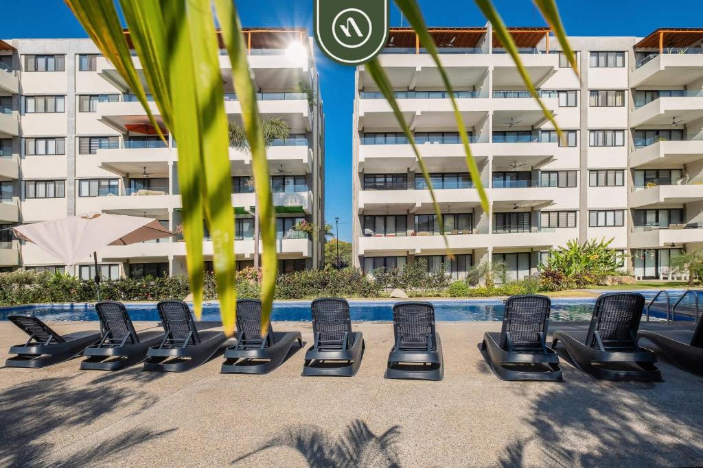 a row of lounge chairs in front of a building at 2BR Condo with Private Terrace - Near to the Beach in Nuevo Vallarta 