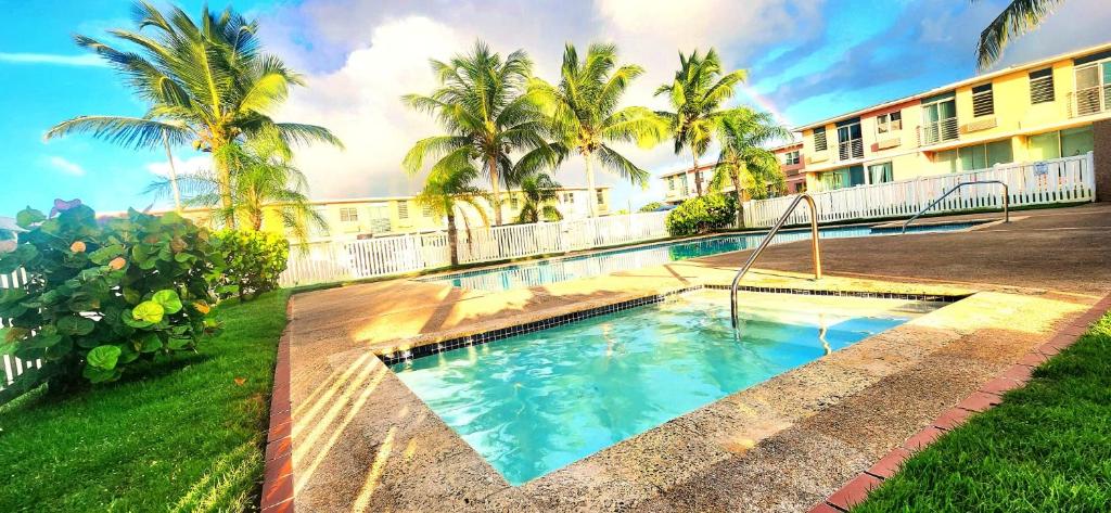 een zwembad voor een gebouw met palmbomen bij Isla Bonita Townhouse - 5 min SJU in Carolina