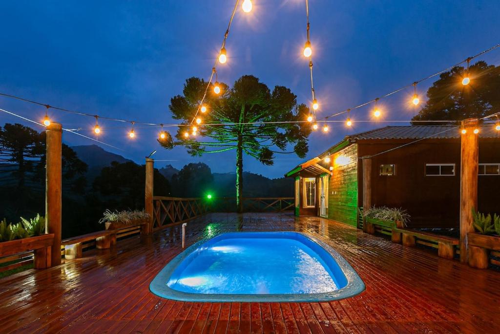 eine Terrasse mit Swimmingpool auf einem Deck mit Beleuchtung in der Unterkunft Altos das Araucárias - one place, great moments! in Alfredo Wagner