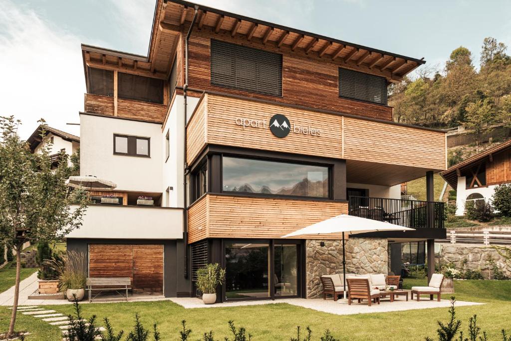 a modern house with wooden facade and a patio at Apart Bieles NEU - Bergoase mit privater Outdoor-Sauna & Massagepraxis in Kauns