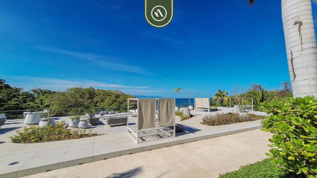 a park with benches and a monument in front of a building at Oceanview 2 BR Condo in Punta Mita - Beach - Pool in Higuera Blanca