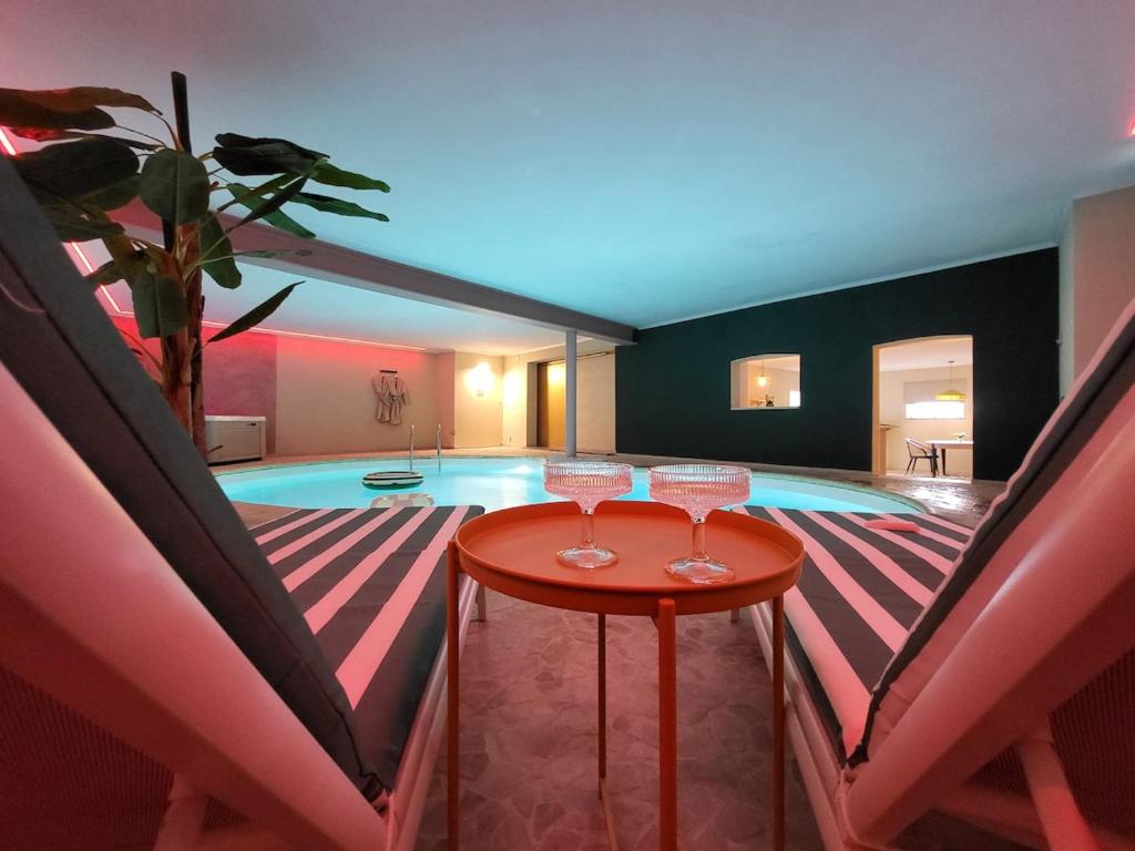 Una piscina con dos copas de vino en una mesa. en Le Beverly Moon - Private Pool & Spa, en Dinant