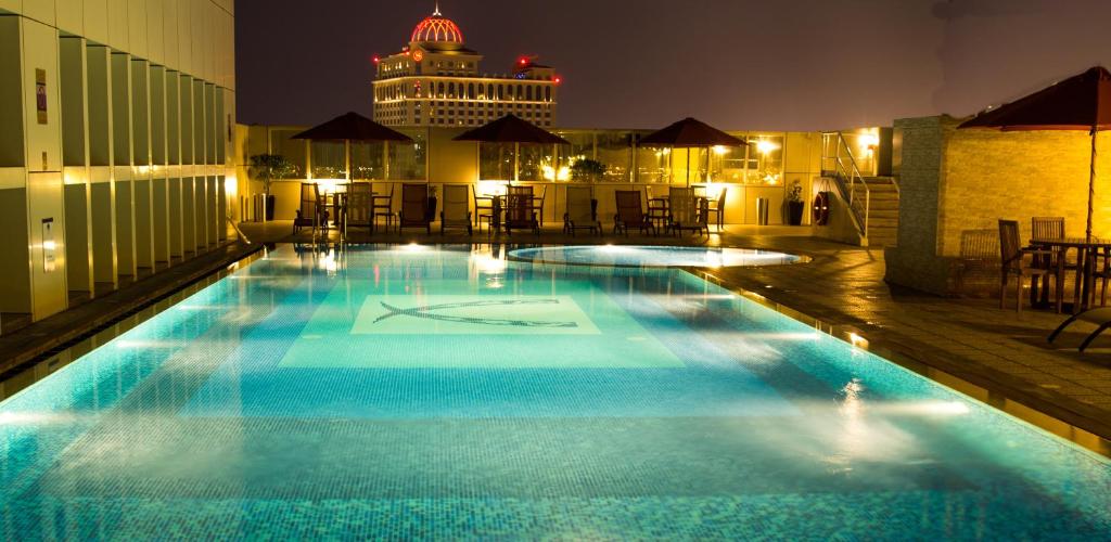 una piscina en la azotea de un edificio por la noche en Ivory Grand Hotel Apartments, en Dubái