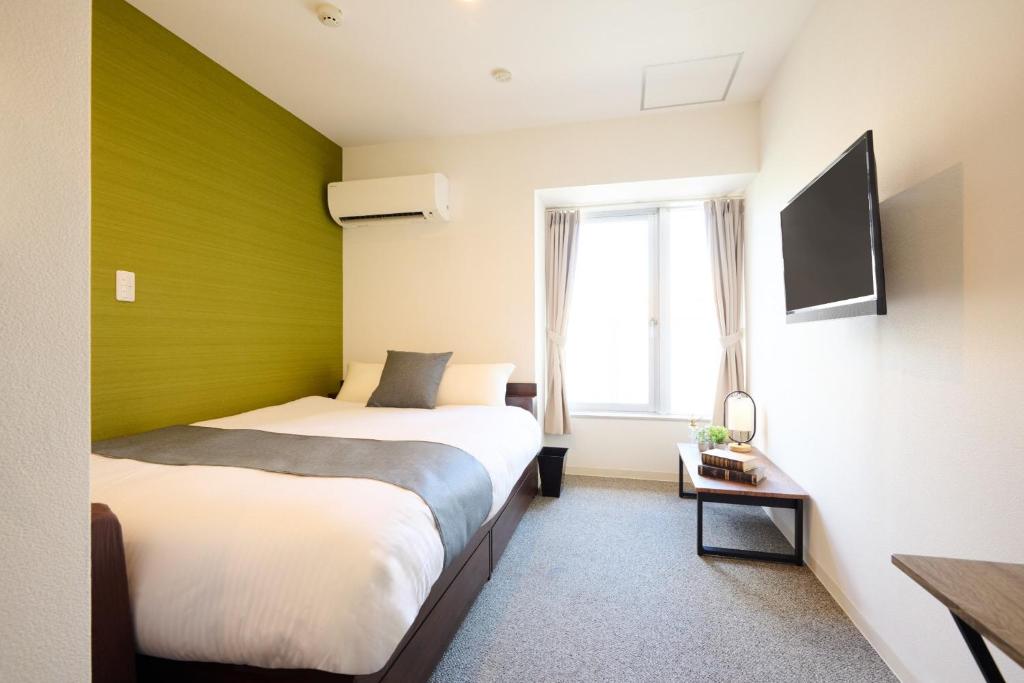 twee bedden in een kamer met een groene muur bij Hotel Stripe Sapporo - Vacation STAY 20489 in Kita-rokujō