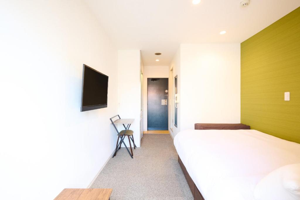 a bedroom with a bed and a tv on a wall at Hotel Stripe Sapporo - Vacation STAY 20493 in Kita-rokujō