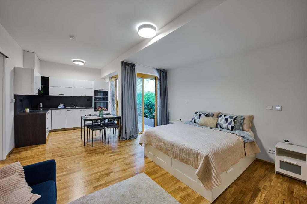 a white bedroom with a bed and a kitchen at Residence Kobrova with free parking in Prague