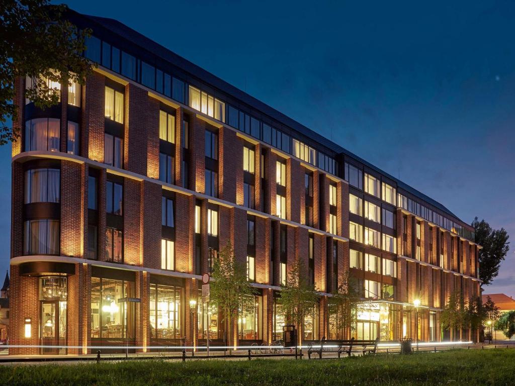 a large brick building with windows at night at The Bridge Wroclaw - MGallery in Wrocław