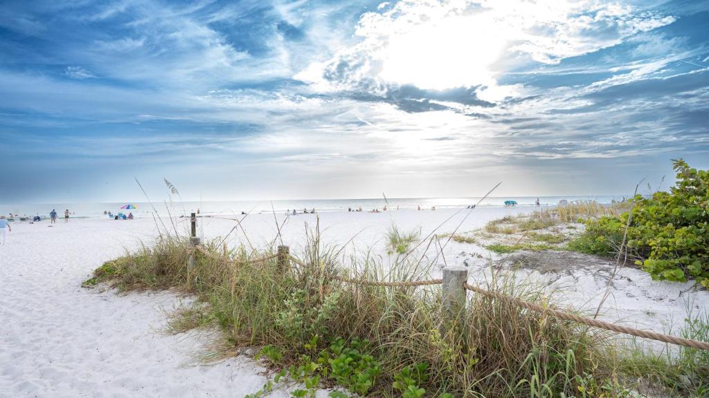 a beach with a fence and people on the beach at Siesta Key Exclusive Beachside Compound 3 Units in Point O'Rocks
