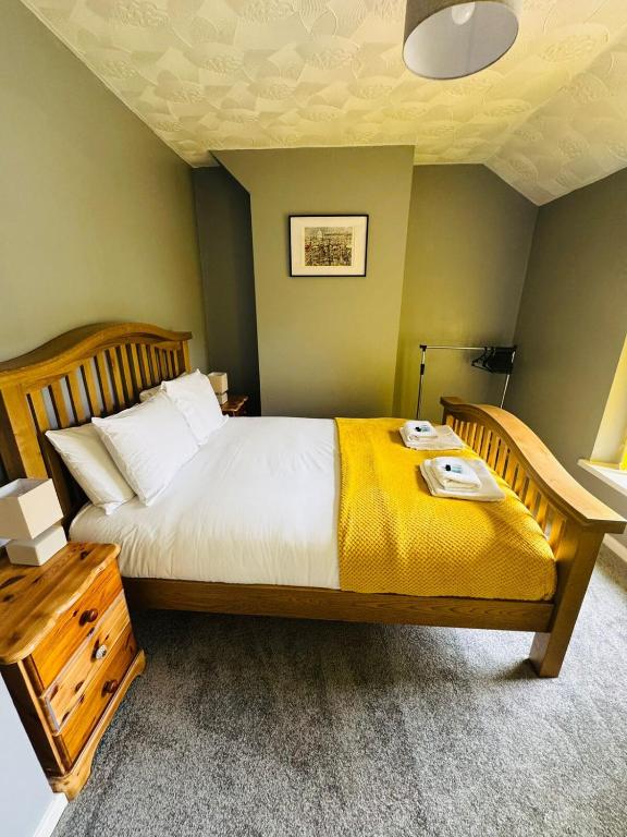 a bedroom with a large bed with a yellow blanket at Gaen - Ty Seren in Abertillery