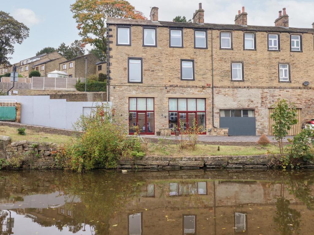 an old brick building next to a body of water at Waters Edge in Skipton