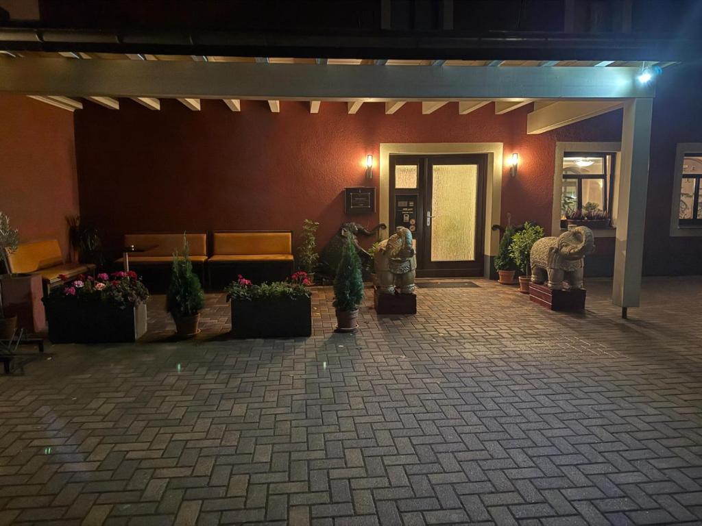 una persona tomando una fotografía de un edificio con plantas en macetas en Pension Rotes Haus, en Großenhain