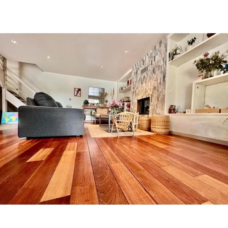 een woonkamer met een bank op een houten vloer bij Spacieuse maison avec piscine in Plédran