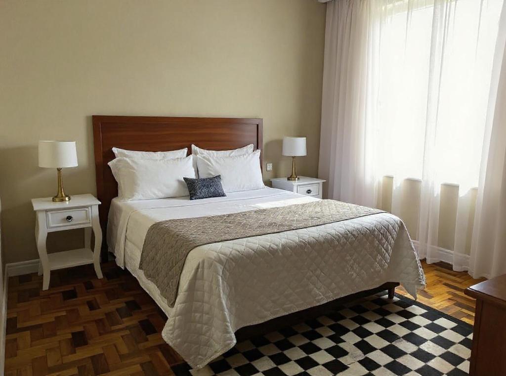Un dormitorio con una cama grande con dos mesas y dos lámparas. en Casa da Vila 2 dormitorios - Centro de Floripa, en Florianópolis