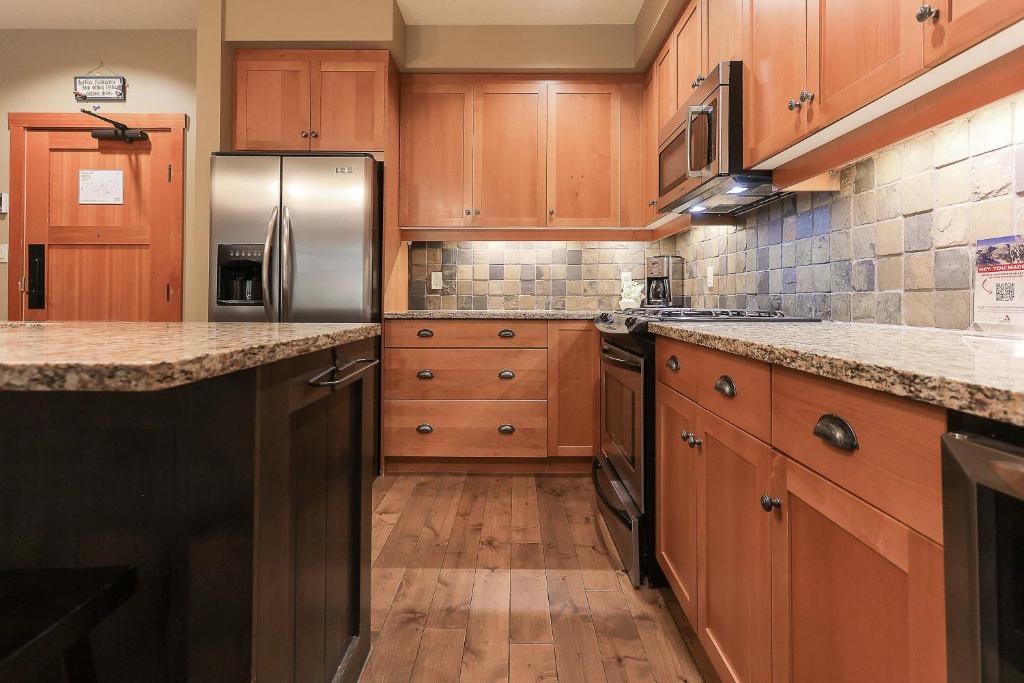 a kitchen with wooden cabinets and a stainless steel refrigerator at Slalom Creek 2 Bedroom & Den in Rossland