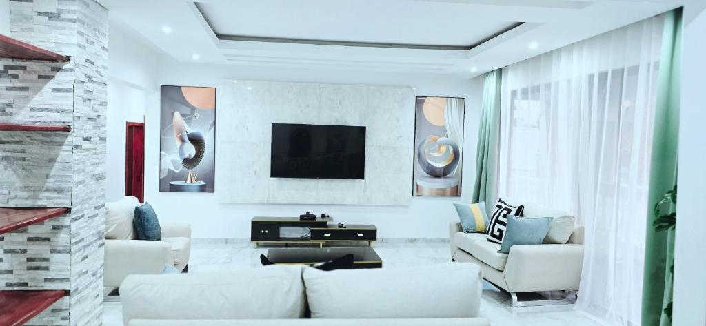 a living room with white furniture and a flat screen tv at Canvas Luxury Villas in Lusaka