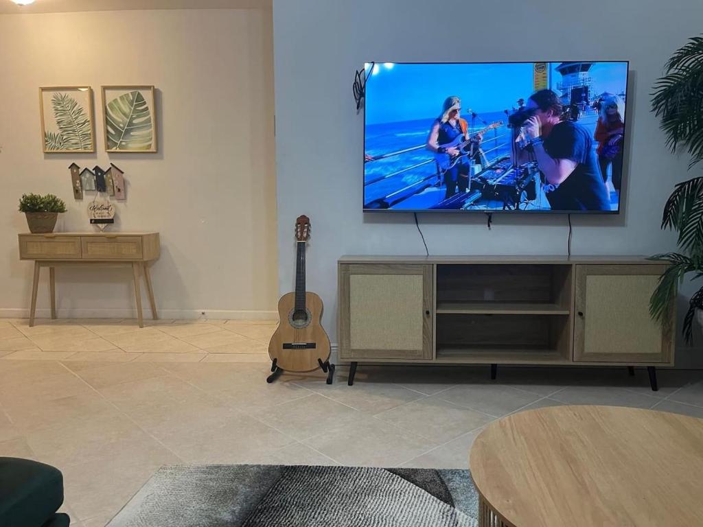 Una sala de estar con un televisor de pantalla plana y una guitarra. en Paradise in Palmetto Bay, with Pool-BBQ-Gazebo., en Rockdale